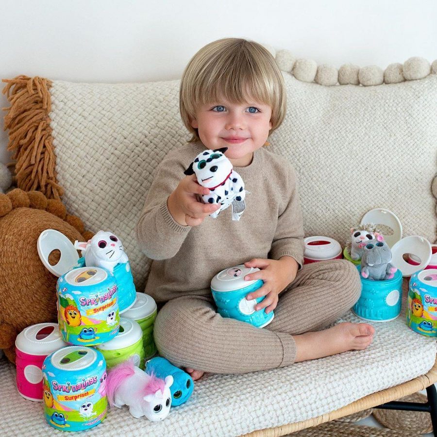 blonde boy sat on a cream sofa playing with Springlings toy animals