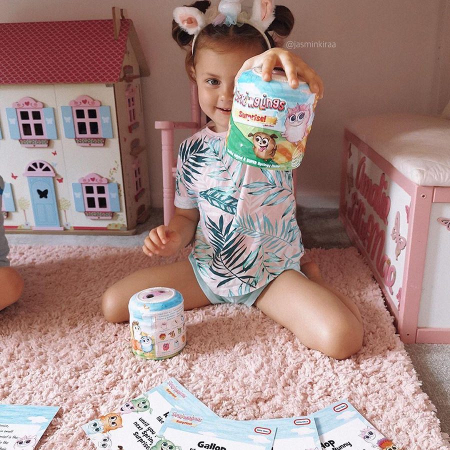 Little girl opening Springlings toys in pink bedroom wearing a unicorn headband