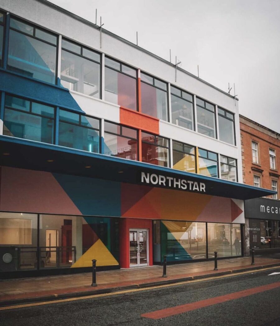 White building with pink, yellow, blue, orange and red angular shaped painted on the outside